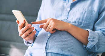 Pregnant mother using her phone to learn about managing pregnancy symptoms