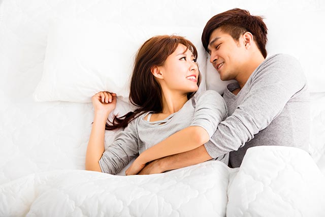 Young asian couple cuddling in bed
