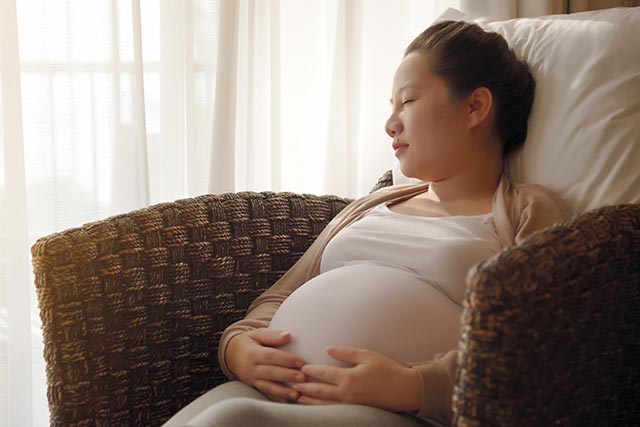 Pregnant woman sitting in recline on the couch and taking a nap