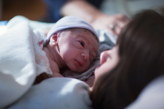 mother smiling while holding her newborn