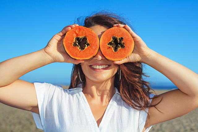 Young woman with two sliecs of papaya on her face