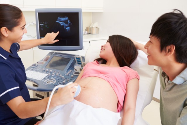 husband and wife with nurse at an ultrasound