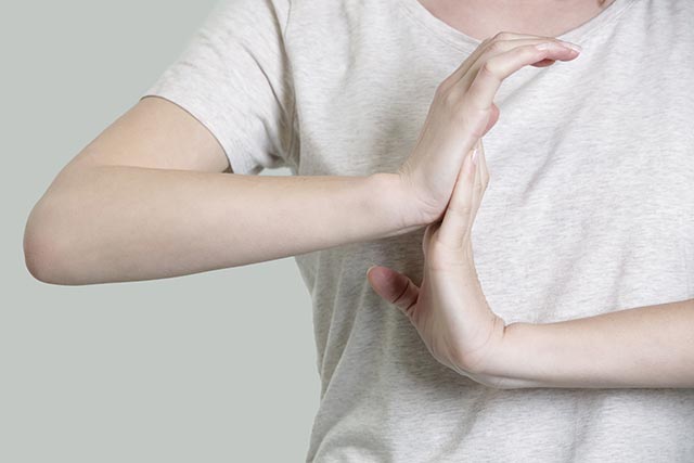 Pregnant woman stretching her wrists to prevent carpal tunnel syndrome