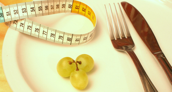 measuring tape and 3 green grapes on a plate