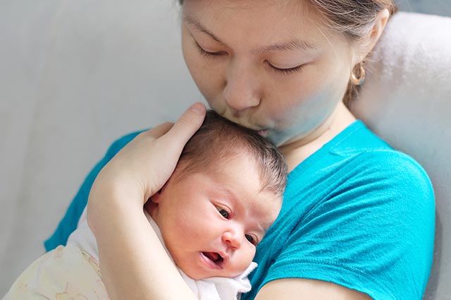 Mother kissing her new born baby on the head