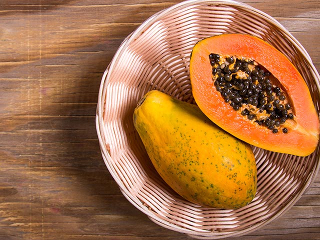 a whole papaya and a split papaya in a basket