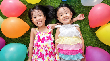 asian-little-chinese-girls-lying-on-grass-amongst-colorful-balloons.jpg